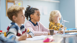 three children listening in a classroom